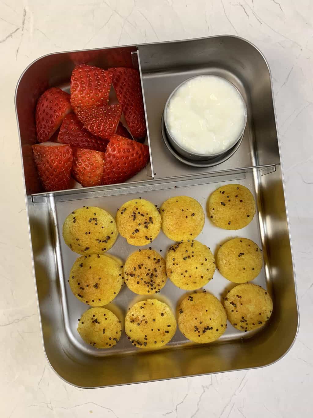 lemon idli, yogurt and strawberries in bento steel lunch box.