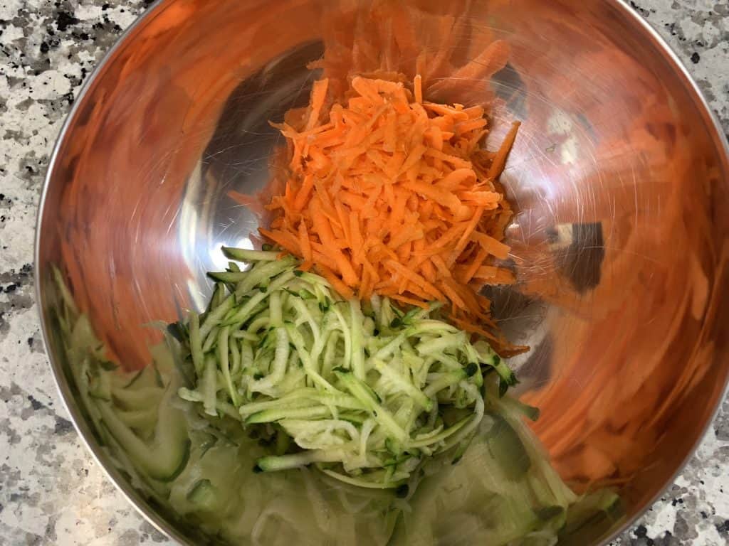 add grated zucchini and carrots to a bowl