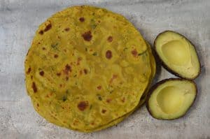 Avocado Paratha served in a plate with halfed avocados on the side