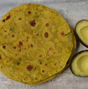 Avocado Paratha served in a plate with halfed avocados on the side