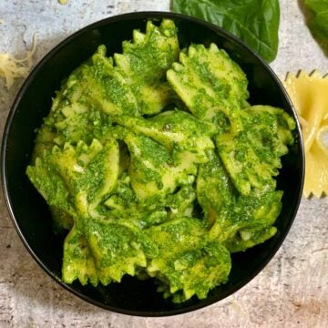 Spinach Pasta served in a black bowl with baby spinach and pasta on side