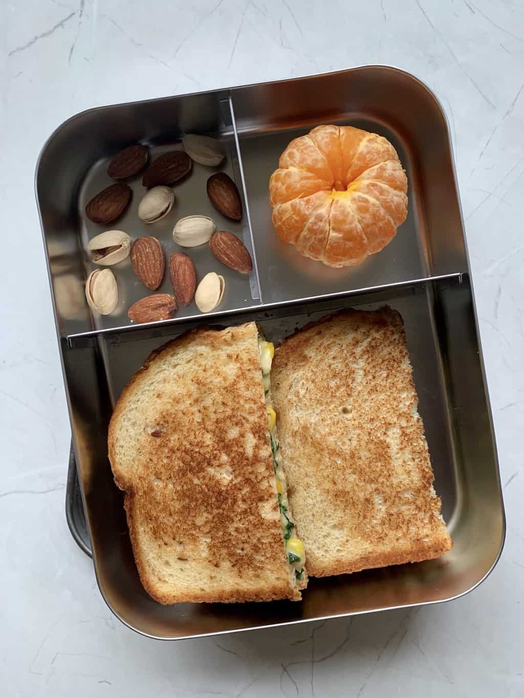 Spinach Corn Sandwich with nuts and orange in steel bento lunch box