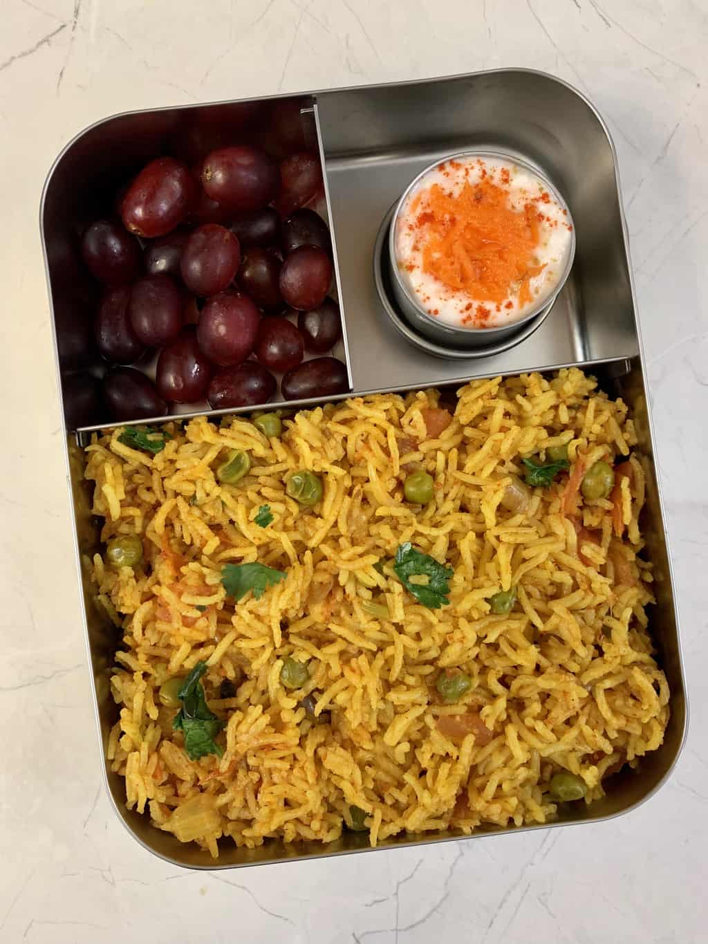 tomato rice with carrot raita and grapes in bento steel lunch box