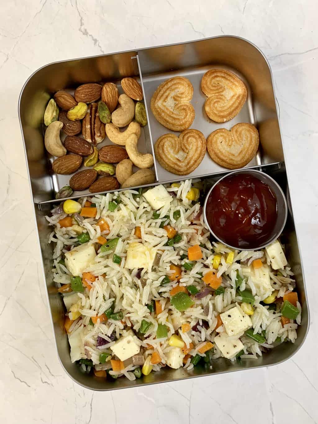 Paneer fried rice with heart shaped cookies and nuts in steel bento lunch box