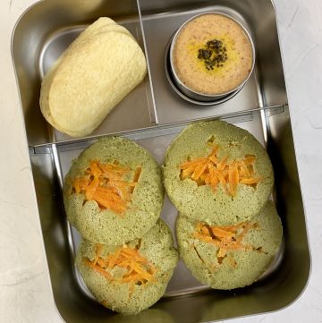 Spinach idli with peanut chutney and chips in bento steel lunch box