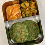 spinach chapati with aloo sabzi and orange in bento steel lunch box