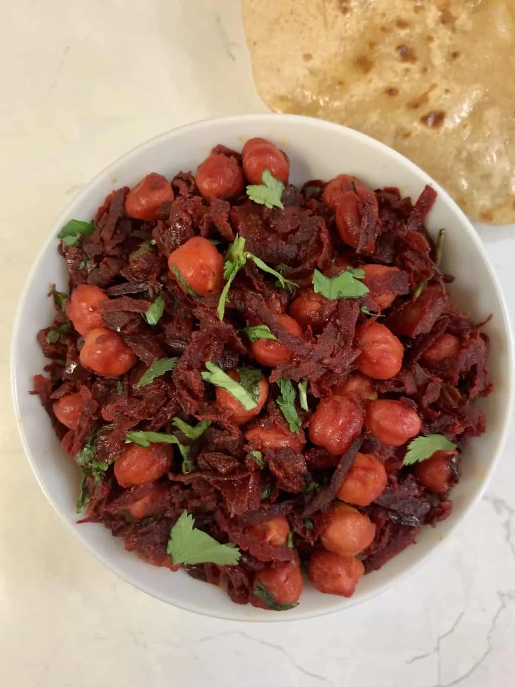 beetroot chickpea stir fry served in a bowl garnished with cilantro with side of chapati