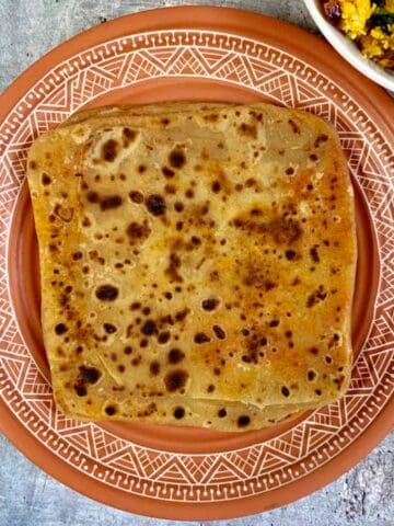 ajwain mirch paratha served on a plate with paneer bhurji on side