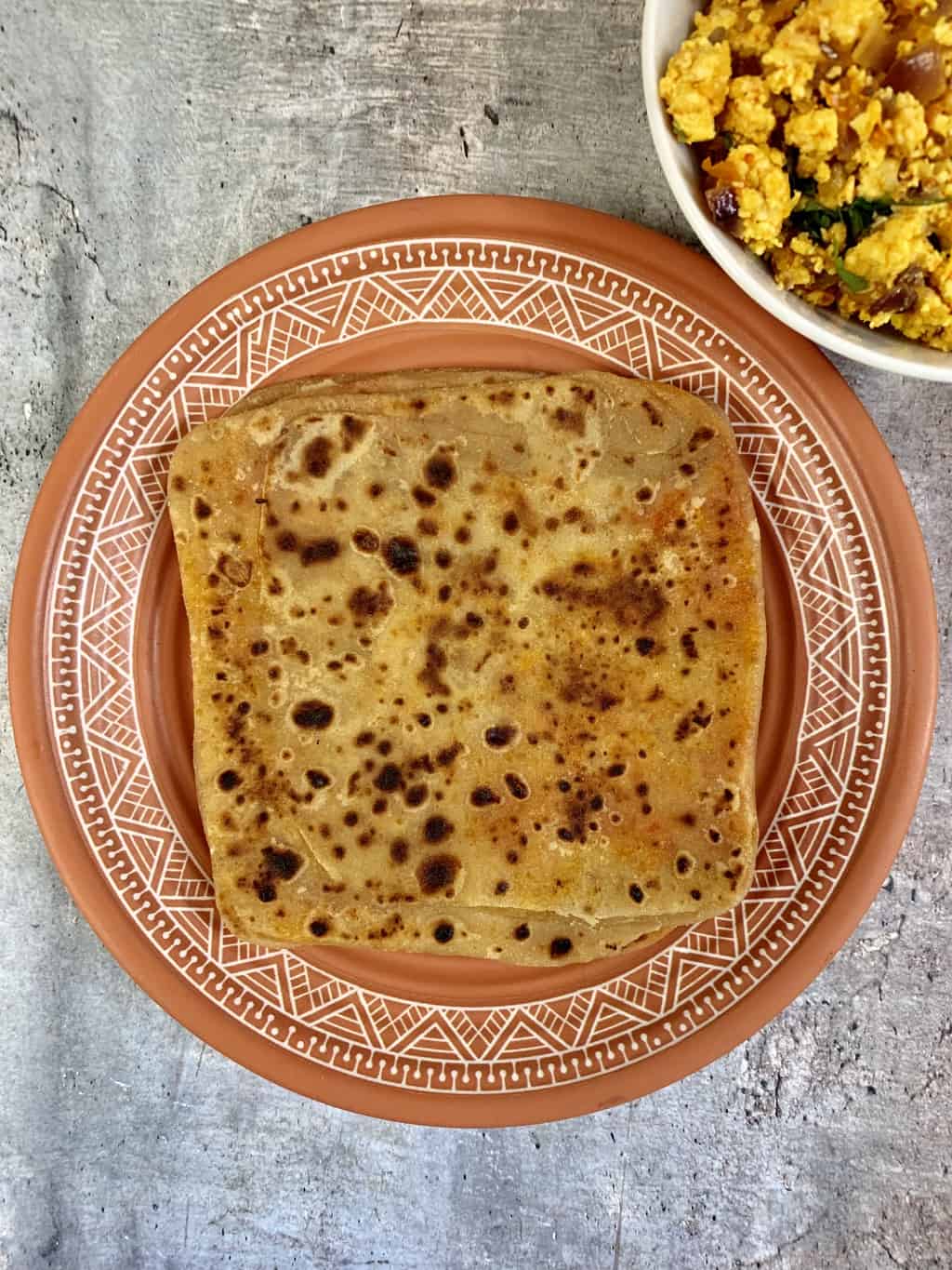 ajwain paratha served on a plate with paneer bhurji on side