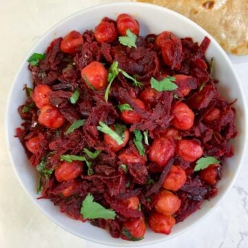 beetroot chickpea stir fry served in a bowl garnished with cilantro and chapati on side