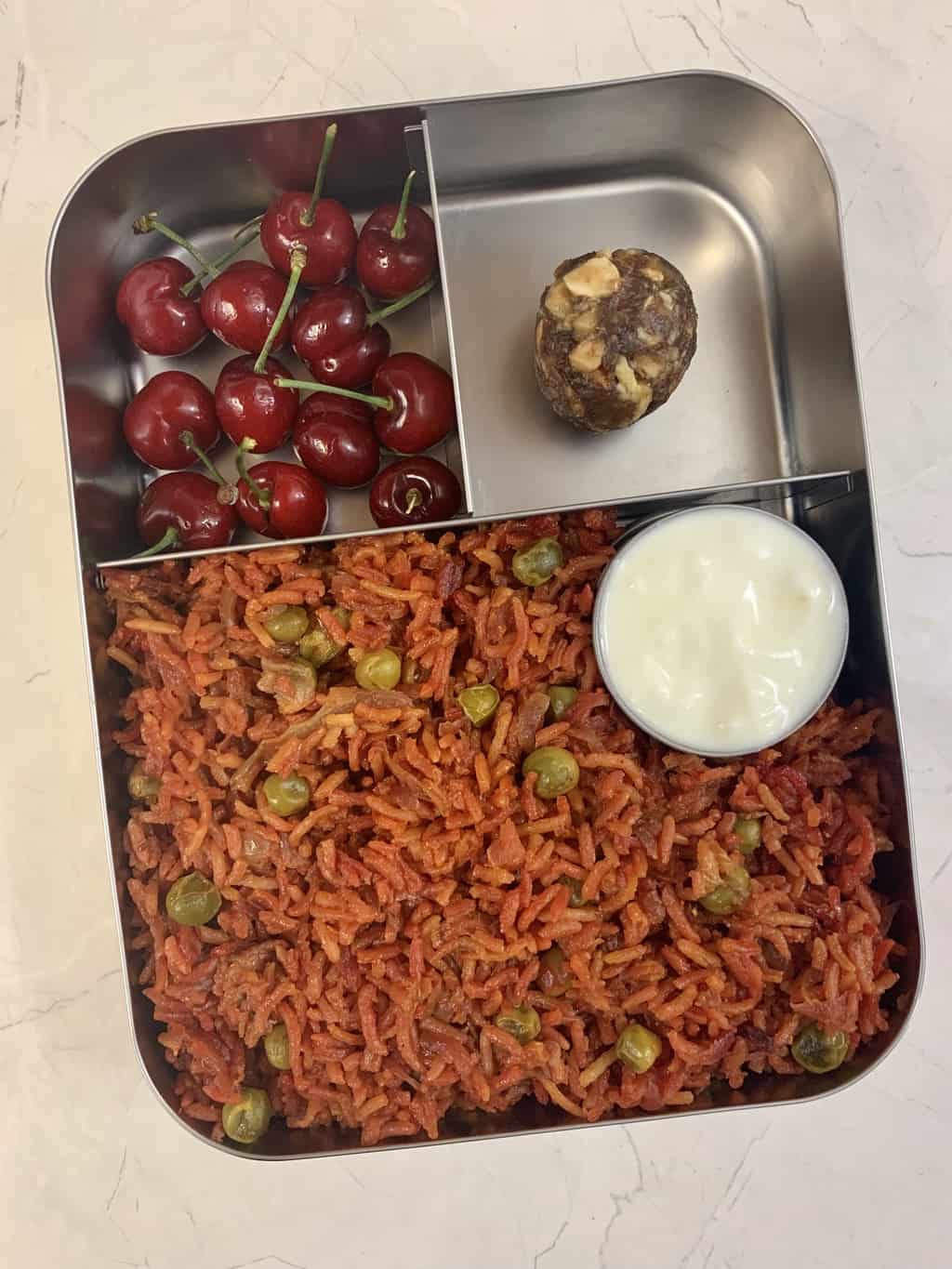 beetroot rice with yogurt, dates and nuts ladoo and cherries in bento steel box.