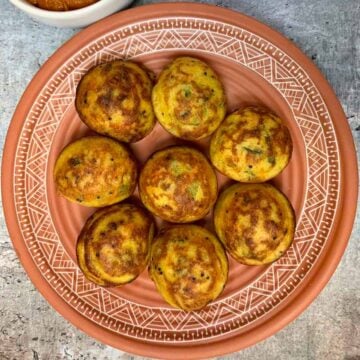 vegetable paniyaram served on a plate with onion chutney on the side