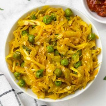 cabbage peas stir fry served in a bowl with pickle on the side