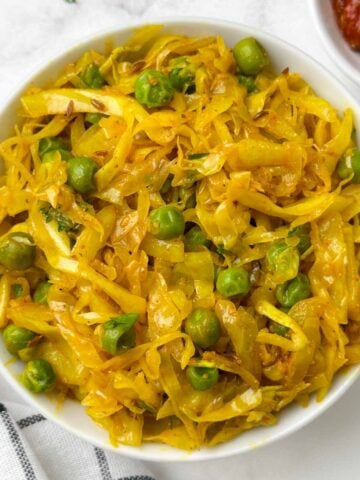 cabbage peas stir fry served in a bowl with pickle on the side