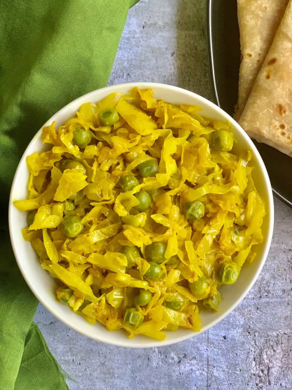 Cabbage Peas Stir Fry served in a bowl with chapati on the side
