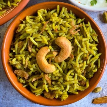 Palak or spinach Biryani served in a bowl with raita on the side