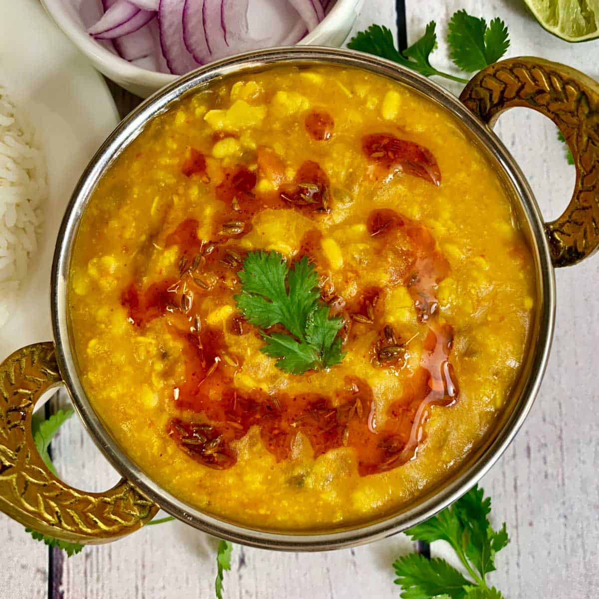 panchmel dal served in a copper bowl with cilantro on side