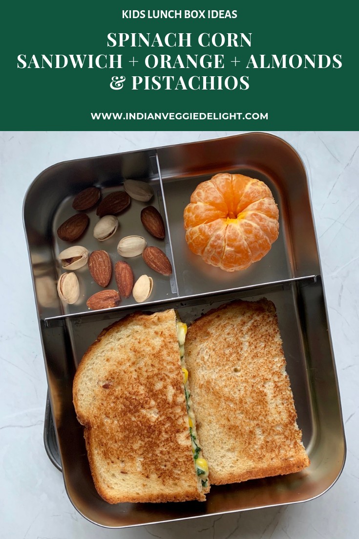 spinach corn sandwich served in a steel lunch box with orange and nuts