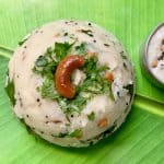 rava upma served on a banana leaf garnished with roasted cashew and coriander leaves with side of coconut chutney