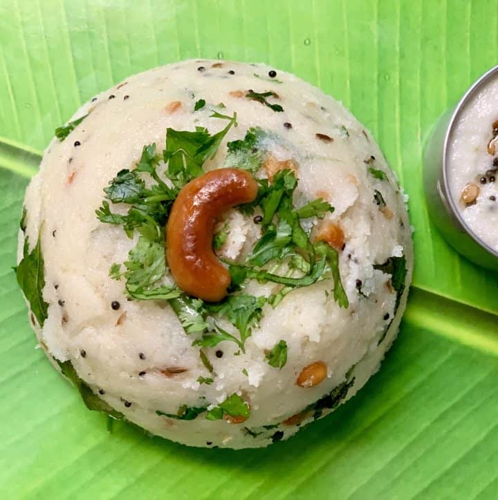 rava upma recipe served on a banana leaf garnished with roasted cashew and coriander leaves with side of coconut chutney