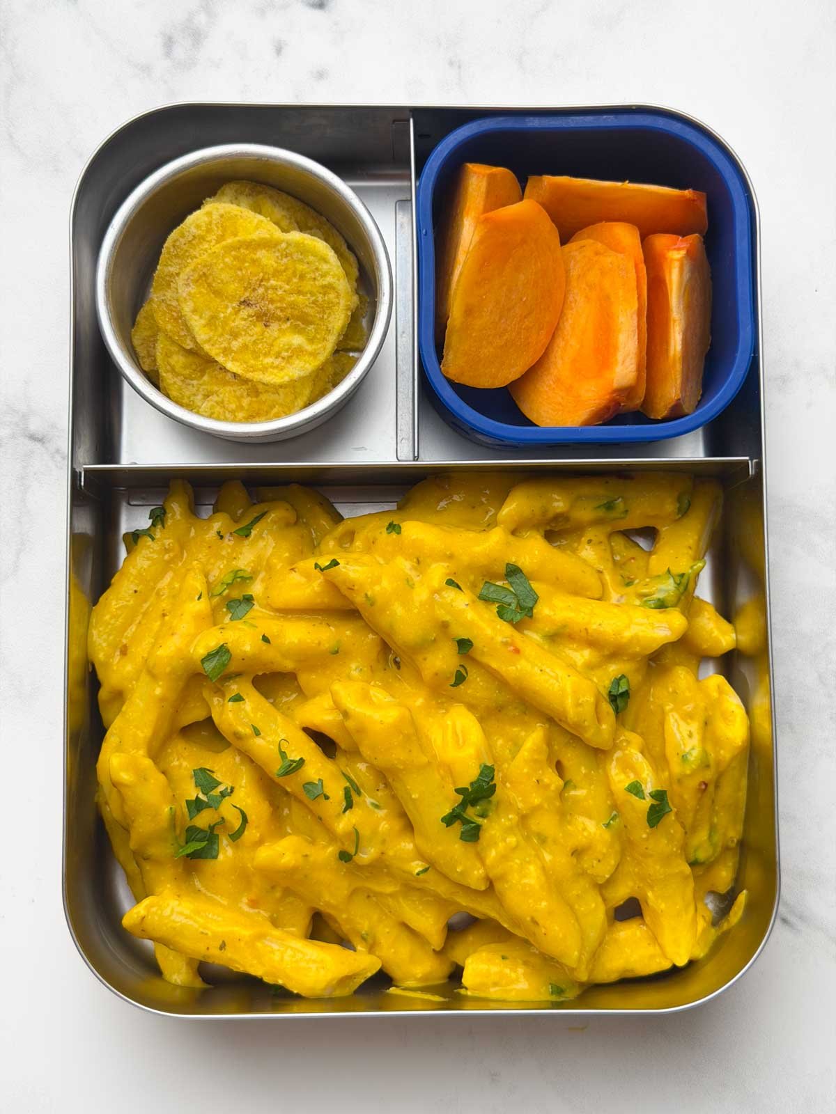 kids lunch bento box pumpkin pasta with banana chips and persimmon fruit.