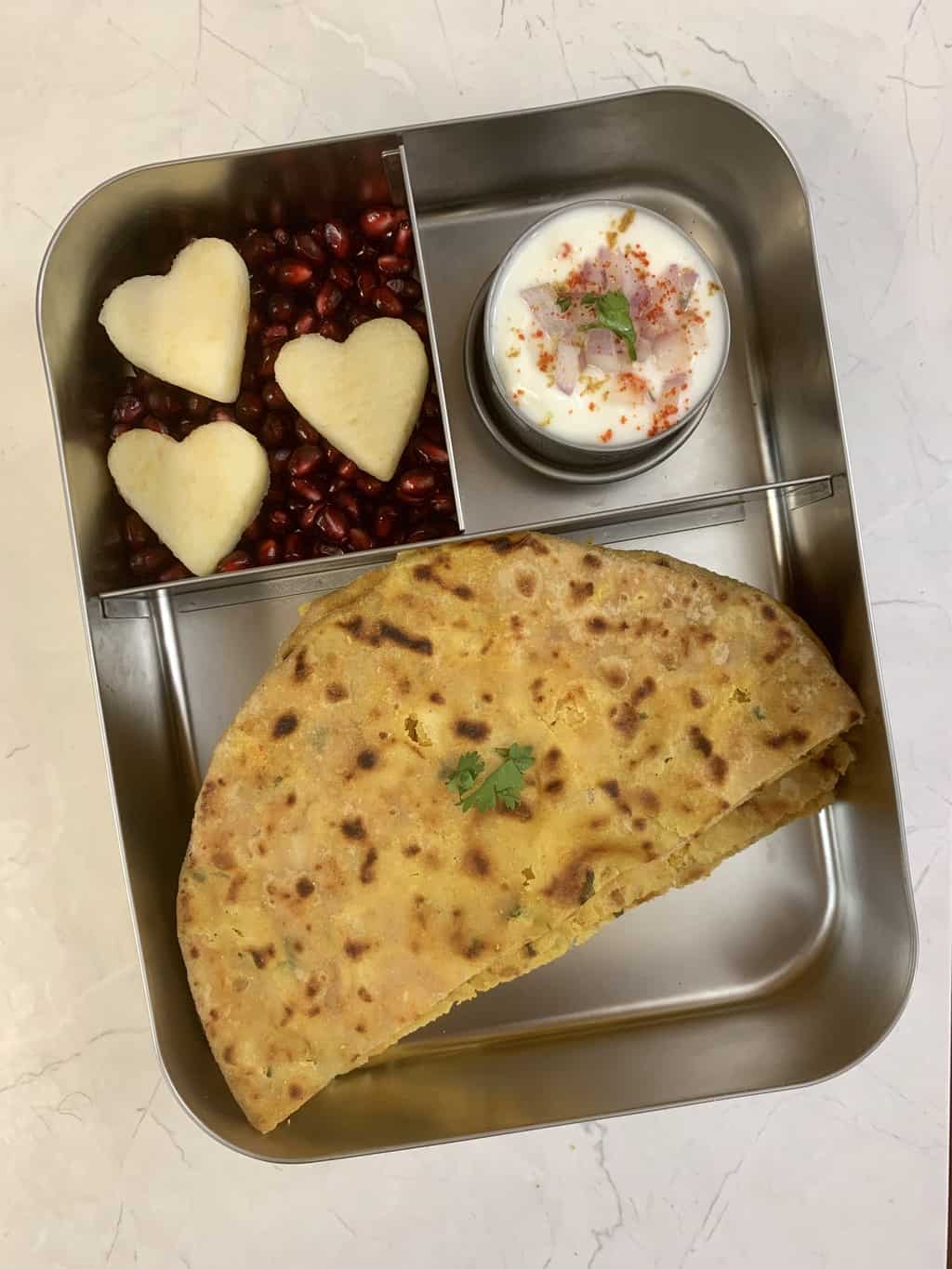 Chole Paratha, Onion Raita, Mixed Fruits in steel bento lunch box.