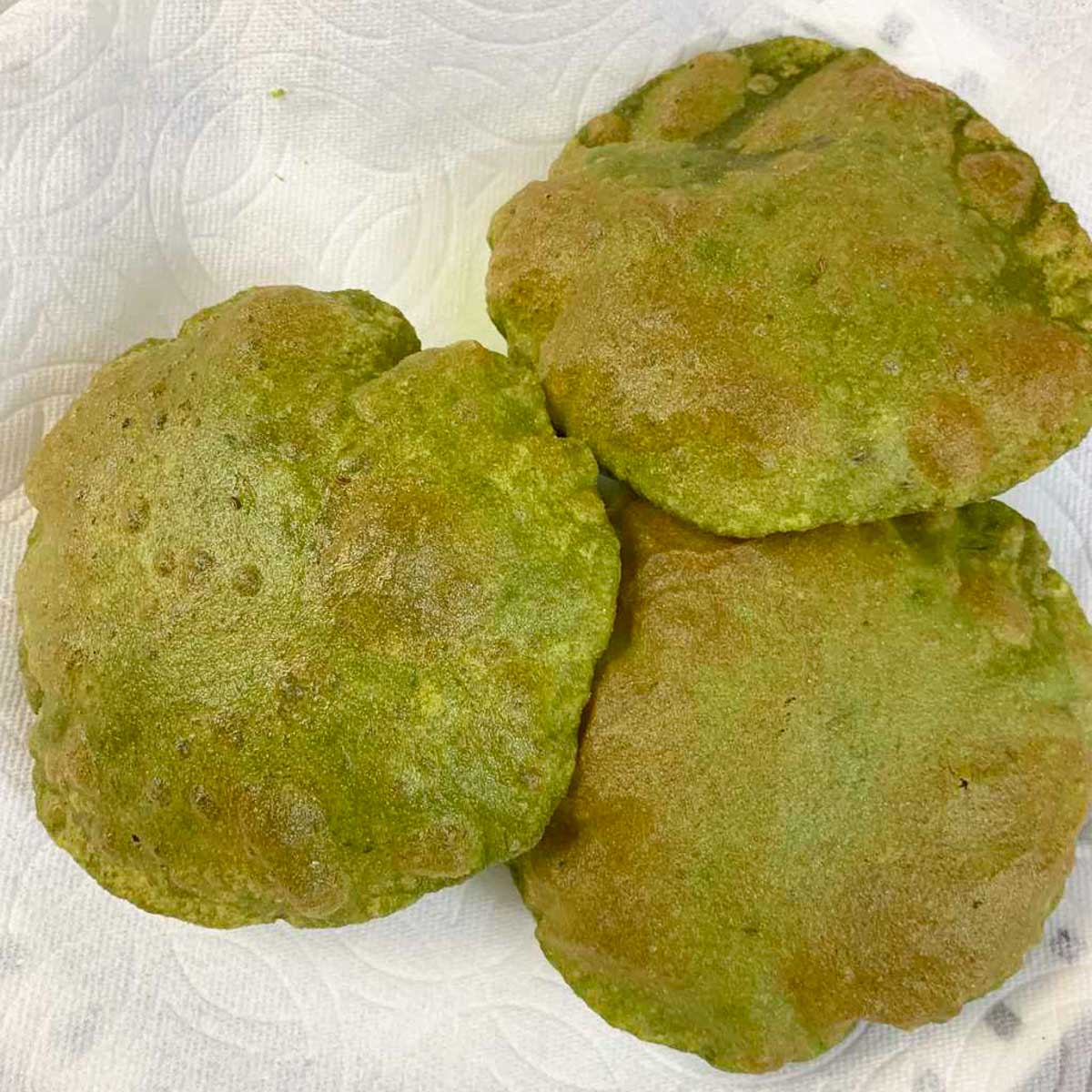 three palak poori on a plate