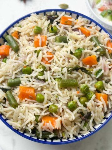 instant pot vegetable pulao served in a bowl with raita on the side