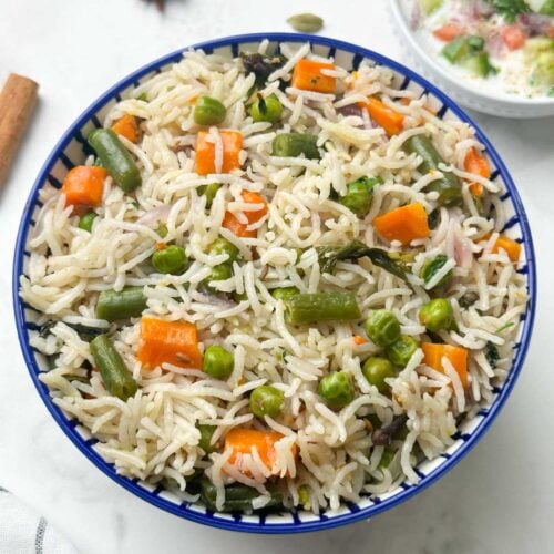 instant pot vegetable pulao served in a bowl with raita on the side