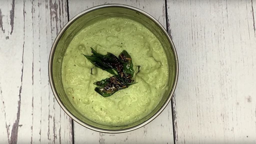 green bell pepper chutney in a blender jar with tempering on the top