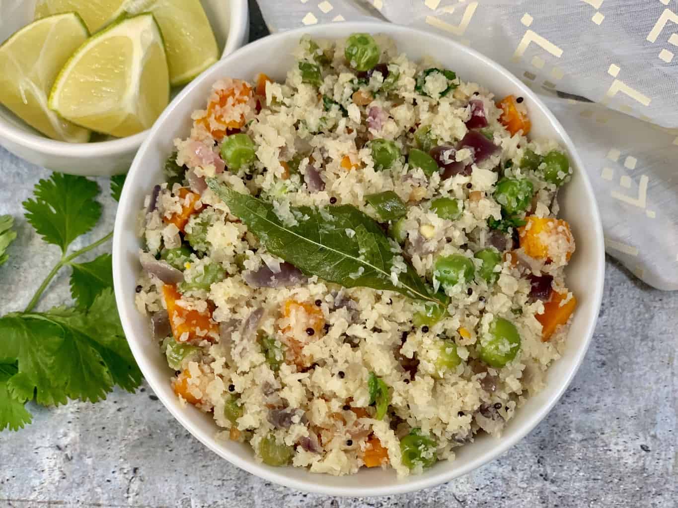 cauliflower upma served in a bowl with lemon wedge and cilantro on the side