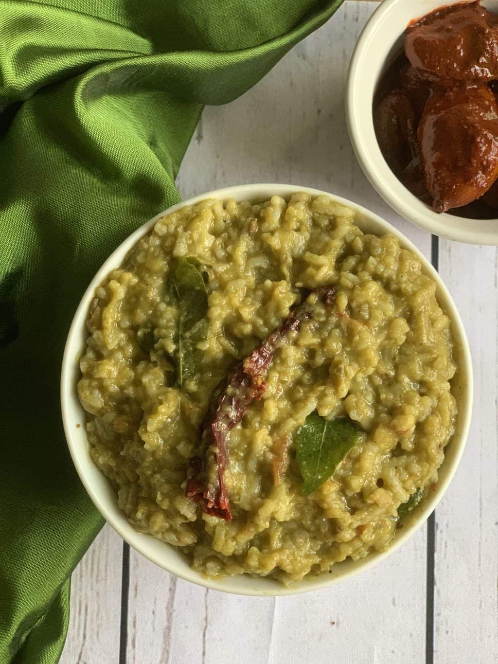 palak khichdi in a bowl with pickle on the side