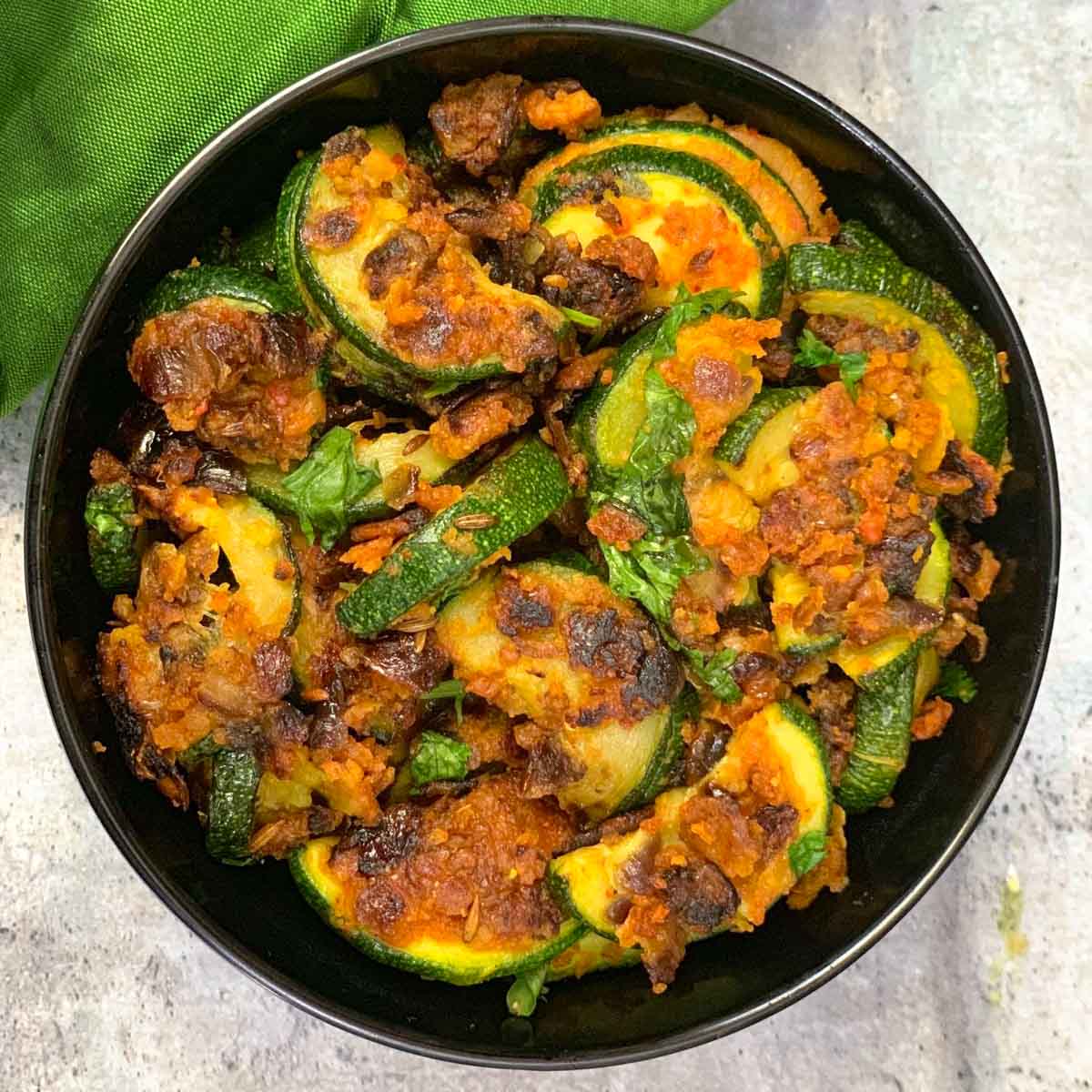 Zucchini Besan Sabzi served in a black bowl garnished with cilantro