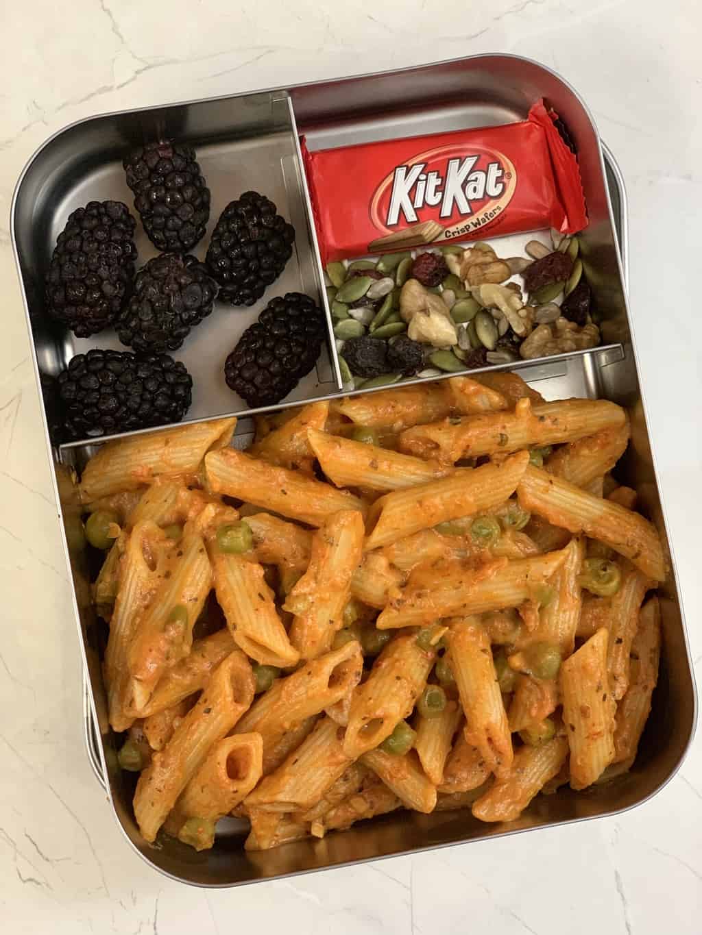 pasta in kids lunch box with kitkat nuts and fruits