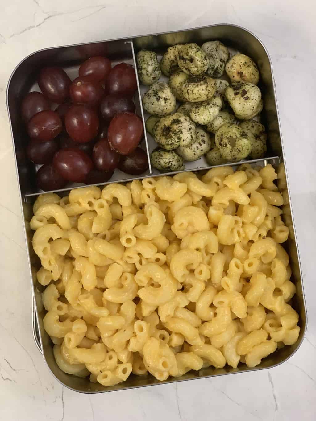 mac and cheese in a steel bento box with grapes and mint makhana on the side