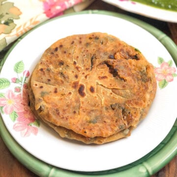 onion paratha served on a plate with curry on the side