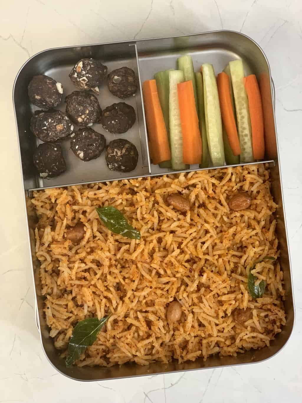 Peanut Rice with carrot, cucumber sticks and chocolate makhana in steel bento lunch box