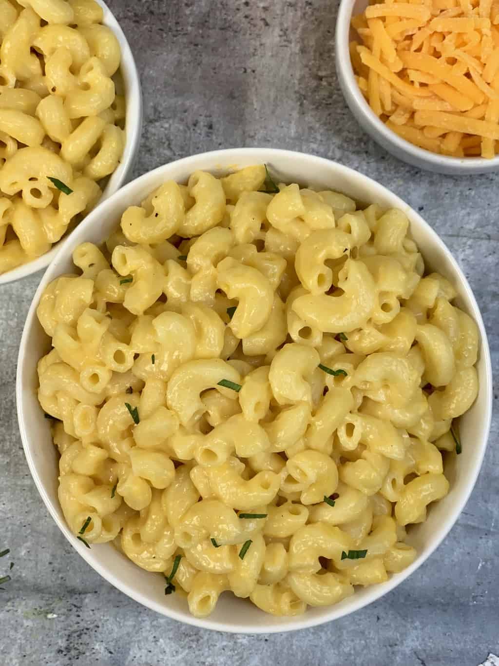 mac and cheese served in two bowls with cheddar cheese on the side in a bowl