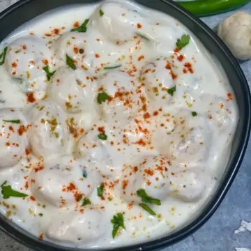 Makhane ka raita served in a bowl garnished with dash of red chillli powder and cilantro