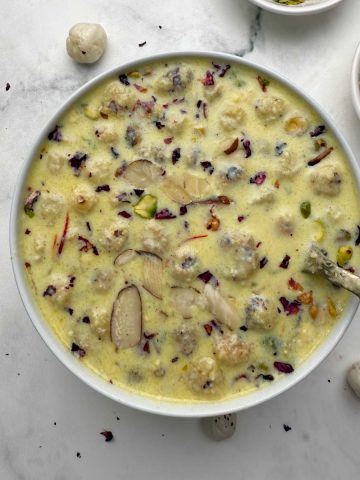 A white bowl full of phool makhana kheer with dry fruits and nuts on the side in small bowls.