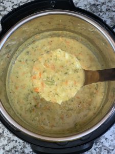 broccoli cheddar soup in instant pot insert with laddle full of soup