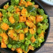 carrot beans poriyal served in a bowl with side of steamed rice and dal