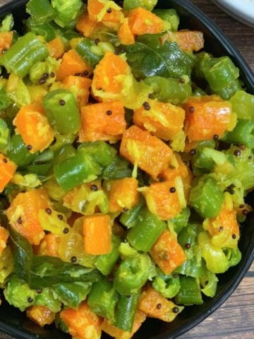 carrot beans poriyal served in a bowl with side of steamed rice and dal