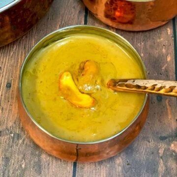 Chana dal payasam served in a samll bowl with spoon garnished with roasted cashews