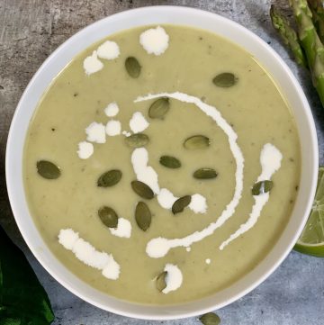 Cream Of Asparagus Soup served in a bowl garnished with pumpkin seeds and cream
