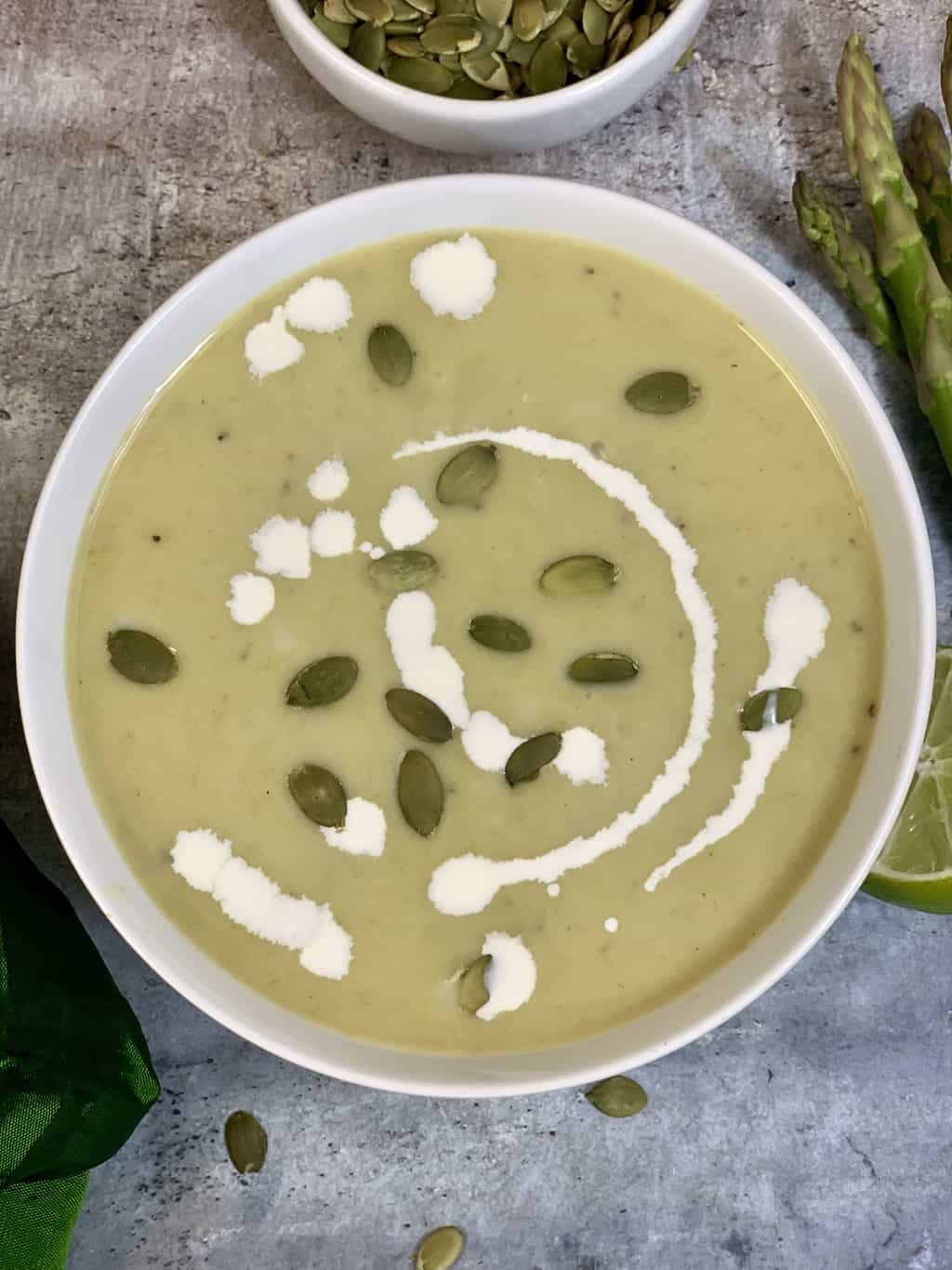 Cream Of Asparagus Soup served in a bowl garnished with pumpkin seeds and cream 