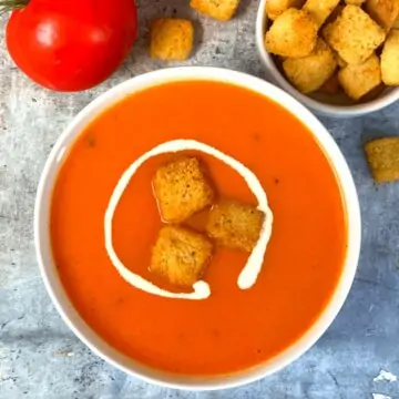 Instant Pot Creamy Tomato Soup served in a bowl with bread croutons and cream on top