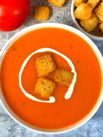 Instant Pot Creamy Tomato Soup served in a bowl with bread croutons and cream on top