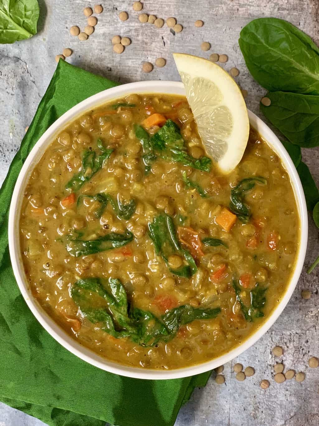 Green lentil soup with coconut milk served in a bowl with lemon wedge on the top