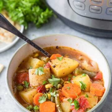 Vegetable soup served in a bowl with a spoon and instant pot behind